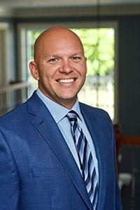 Bald man wearing a blue suit smiling